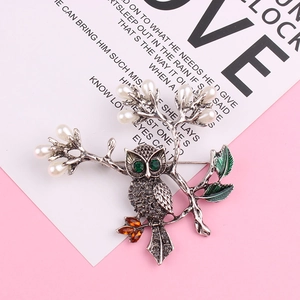 Broche chouette chic avec strass gris, perles blanches et feuilles en émail vert sur branche