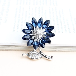 Detailed macro shot of blue crystal sunflower brooch on a book, showing intricate petal craft