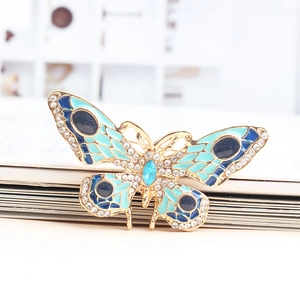 Detailopname van vlinderbroche met blauw emaille en fonkelende kristallen afwerking