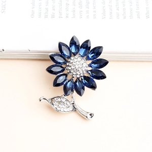 Macro shot of silver sunflower brooch with blue crystal petals and micro-pave accents