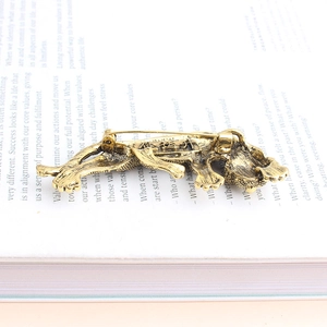 Detailed close-up of retro gold cheetah brooch with scale texture on an open book