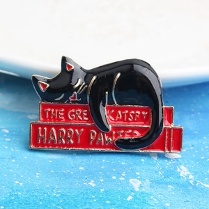 Detail of Harry Pawter black cat enamel pin with golden edges on stacked red books