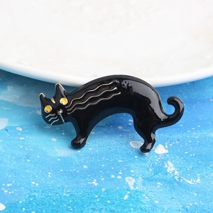 Detalle del broche de gato de esmalte negro con detalles dorados y ojos amarillos