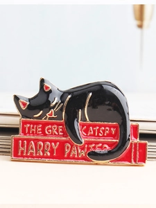 Close-up of enamel cat brooch with The Great Catspy and Harry Pawter book design