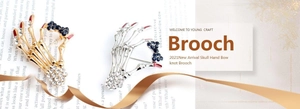 Macro detail of skeleton hand brooch with rhinestones and red fingertips in gold and silver