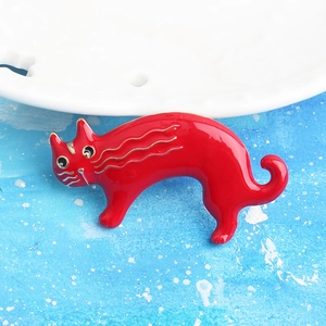 Detalle de un broche de gato en esmalte rojo vibrante con líneas doradas artísticas