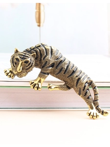 Detailed close-up of a vintage golden cheetah brooch with black enamel stripes on a book