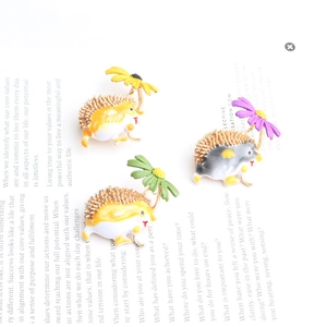 Détail de trois broches hérisson en émail avec des accents floraux colorés sur un magazine