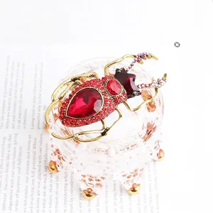 Macro detail of beetle brooch with red ruby stones and crystal accents on a magazine