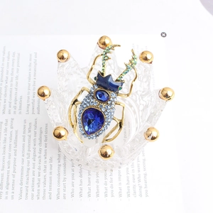 Detailed close-up of a blue beetle brooch with zircon inlay in a glass crown holder