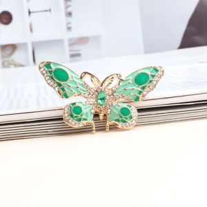 Detail van vintage vlinderbroche met groen emaille en glanzende witte strass