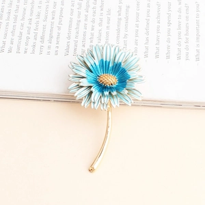 Detailed view of daisy flower brooch with blue and white petals on a book page