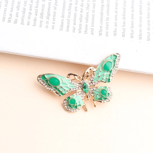 Detailopname van vlinderbroche met groen emaille en glinsterende witte strassteentjes
