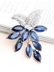Detailansicht der silbernen Blumenbrosche mit blauen Kristallen auf einem Magazin