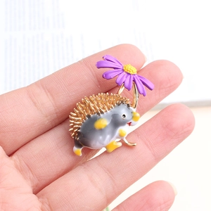 Gros plan d'une broche hérisson avec fleur violette tenue à la main pour taille