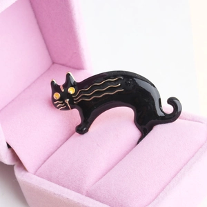 Lindo broche de gato en esmalte negro con bordes dorados en una caja de terciopelo rosa