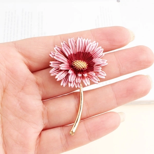 Close-up of pink daisy brooch with layered petals and golden stamen detail