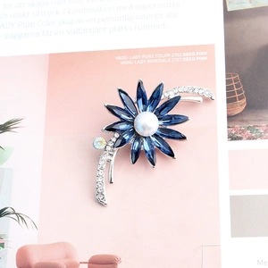 Détail macro d'une broche fleurie avec cristaux bleus et incrustation de perle centrale