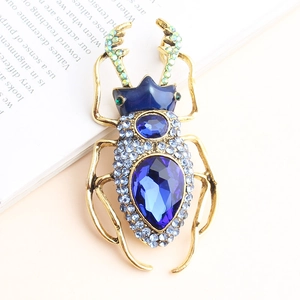 Vintage golden insect brooch featuring large blue rhinestones and colorful accent crystals
