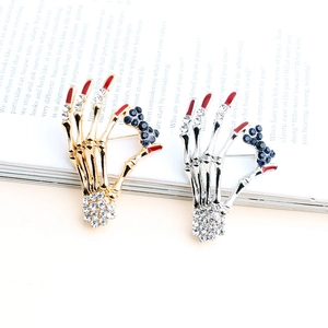 Vintage skeleton hand brooches in gold and silver with blue rhinestone bow details