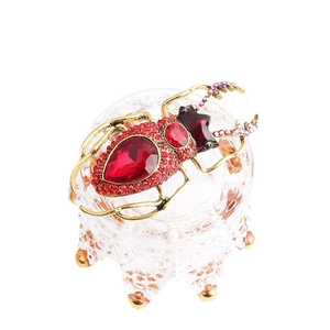 Vintage beetle brooch in antique gold metal with red crystals on a glass crown stand