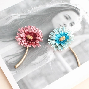 Elegant enamel daisy brooches in pink and blue on an illustrated magazine background