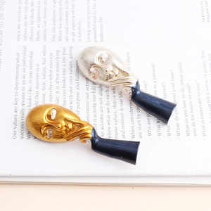Artistic abstract face drop earrings set in gold and silver with black cylinders