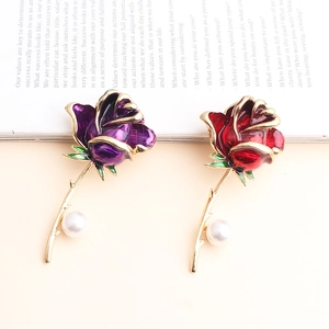 Detail of flower enamel brooches in red and purple colors with white pearl accents