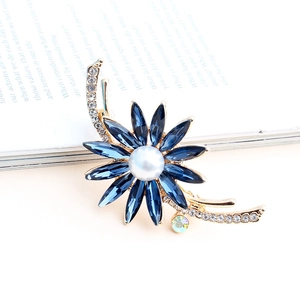 Broche fleur dorée élégante avec cristaux bleu marine, perle blanche et accents de strass