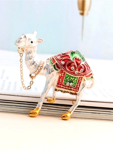 Détail d'une broche alpaga sertie de cristaux avec émail rouge et vert sur des livres