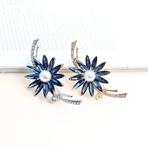 Vue détaillée de broches fleurs avec cristaux bleu marine et perles sur un magazine