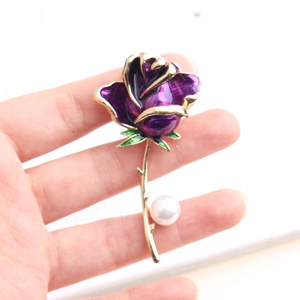 Elegant purple enamel rose brooch with gold stem and white pearl accent held in hand
