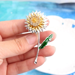 Detailed view of bicolor sunflower brooch with silver petals and green enamel leaf detail