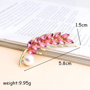 Elegant gold wheat ear brooch with pink crystals and white pearl on vintage book pages