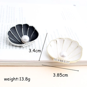 Fashionable black and white pearl shell brooches with rhinestones on magazine background
