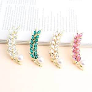 Detail of wheat ear brooches in four colors with crystals and large pearls on a magazine