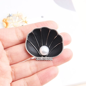 Detail of shell brooch with black enamel, a large pearl, and rhinestone accents