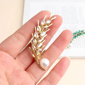 Macro view of gold wheat brooch with champagne crystals and a white pearl accent