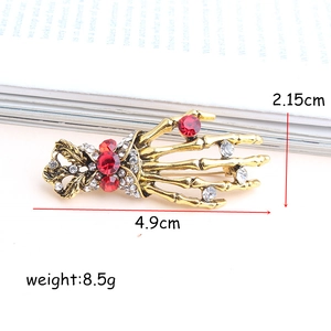 Vintage gothic skeleton hand brooch with red crystals and gold-plated finish