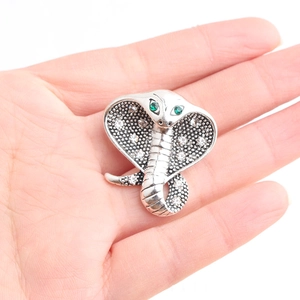 Detailed view of silver snake brooch with green gem eyes and sparkling white crystals