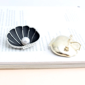 Detail view of pearl shell brooch with black enamel inlay and sparkling rhinestones