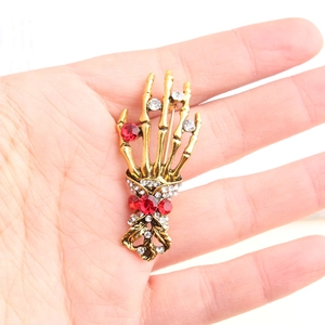 Vintage gold skull hand brooch with red gemstones and sparkling rhinestones for clothing