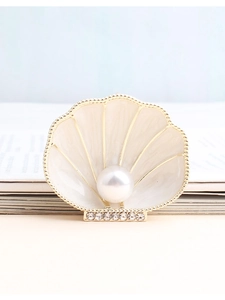 Detailed close-up of shell-shaped brooch with cream enamel and white pearl inlay
