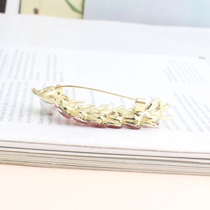 Detailed back view of a golden wheat brooch with a long pin clasp on a book background