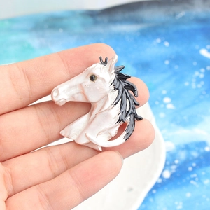Elegant pearl white horse head brooch with black details held in hand for scale