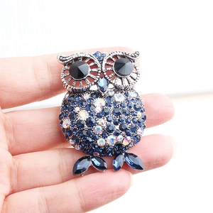 Detailed close-up of a blue rhinestone owl brooch held in hand for size reference