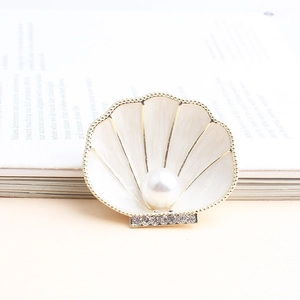 Elegant shell-shaped brooch with white enamel, gold trim, and a centered pearl decoration