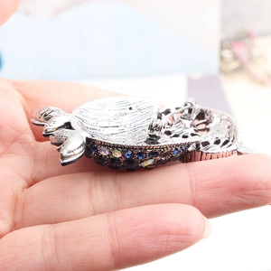 Close-up of owl brooch back with silver metal pin and blue rhinestone claw setting