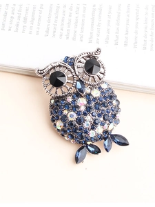 Detailed close-up of retro owl brooch with multi-color blue crystals on a book background