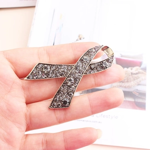 Detail of vintage ribbon brooch with dark rhinestones held by hand for size reference